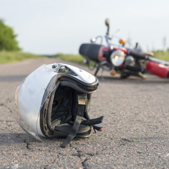 A motorcycle accident on a road with a helmet on the floor.
